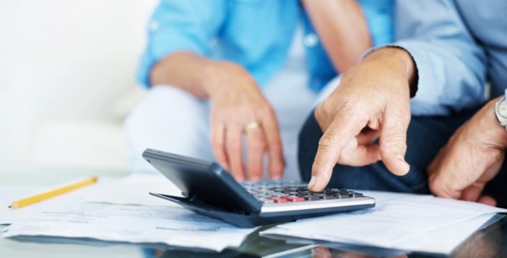 Mannlige henner trykker på kalkulator med en kvinne ved siden av