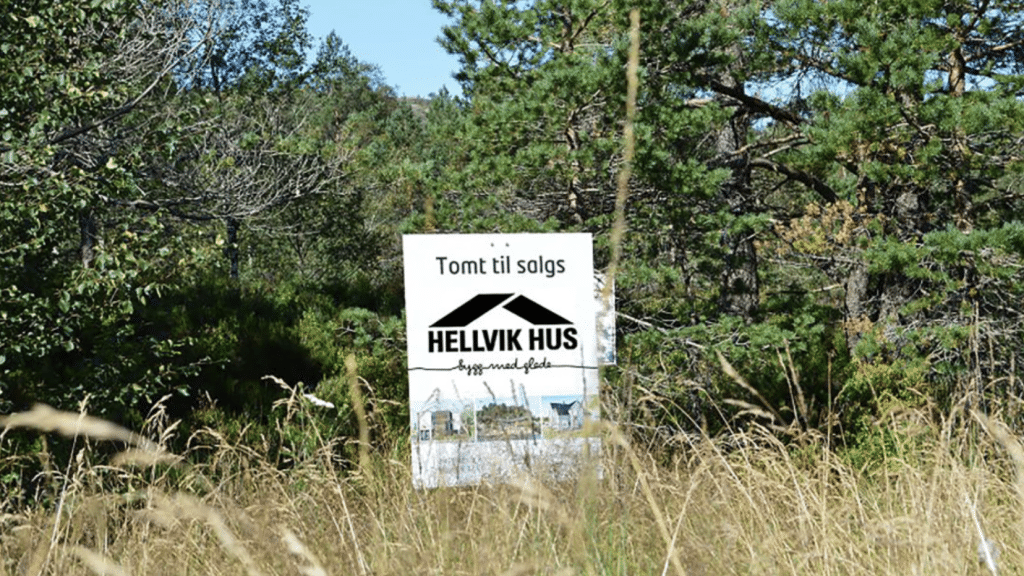 Tomt til salgs skilt på gresset fra hellvik hus